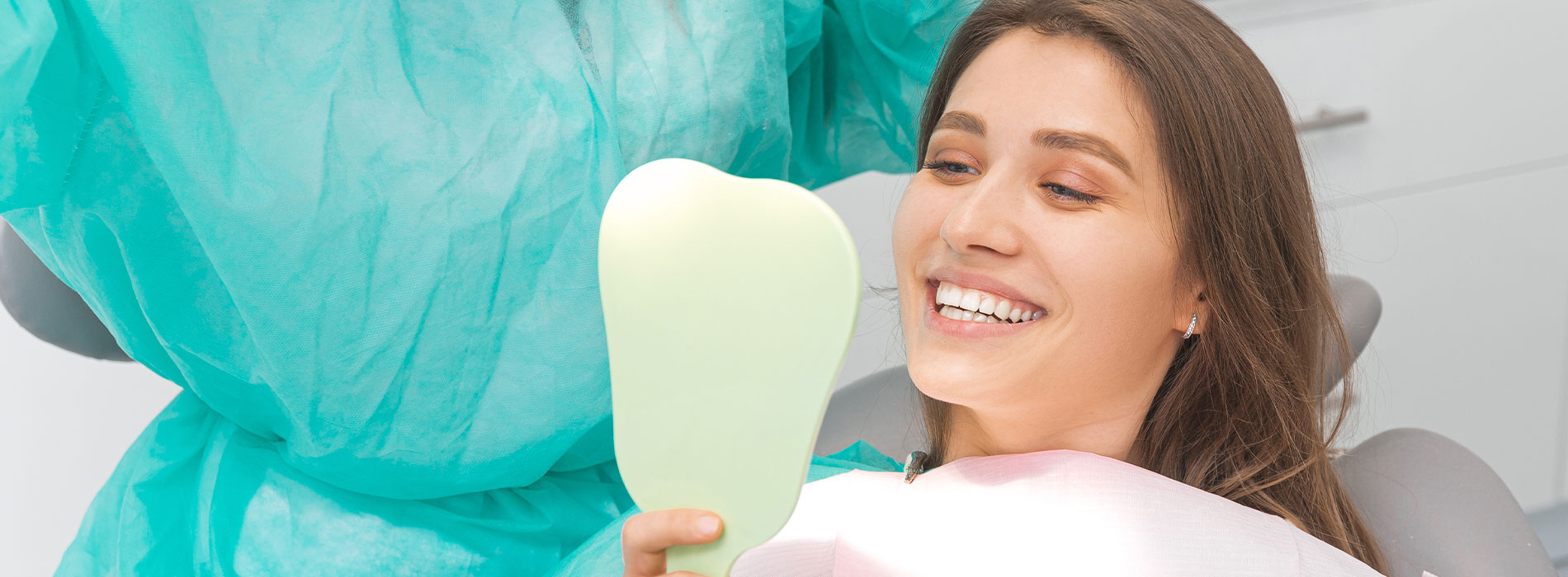 The image is a photograph of a woman with light skin, smiling at the camera. She appears to be in her late twenties or early thirties and has long hair. Her eyes are looking directly at the camera, and she is holding up her index finger near her mouth as if she s making a point or emphasizing something. The background is plain and light-colored, which suggests that this could be a stock photo used for various purposes such as advertising, personal branding, or lifestyle content.